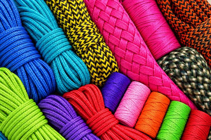 Meadas e rolos de corda e cordão da Joay, lado a lado, em azul, turquesa, verde, amarelo com preto, pink, roxo, laranja e vermelho